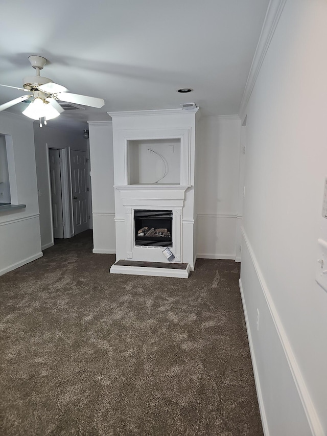 unfurnished living room featuring dark colored carpet, ceiling fan, ornamental molding, and a fireplace