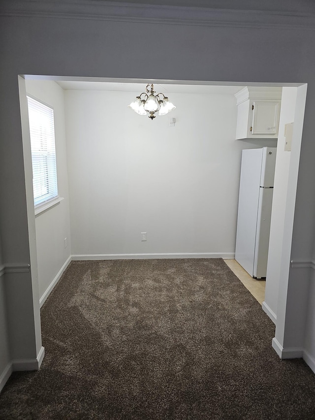 unfurnished dining area featuring carpet flooring, crown molding, and a notable chandelier