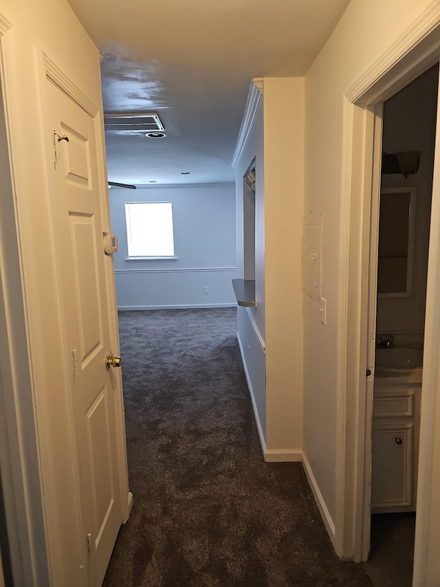 hall with dark colored carpet, ornamental molding, and sink