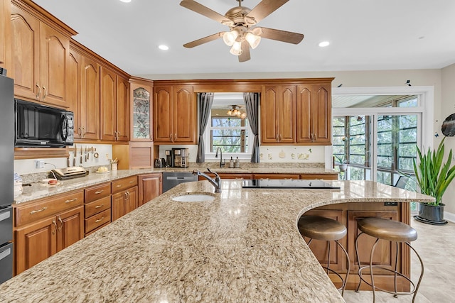 4702 Blockhouse Ln, Hollywood, SC 29449 - kitchen featuring appliances with stainless steel finishes, light stone countertops, brown cabinetry, a kitchen bar, and recessed lighting