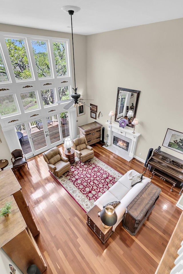 4702 Blockhouse Ln, Hollywood, SC 29449 - living area featuring wood finished floors, a glass covered fireplace, a ceiling fan, and a high ceiling