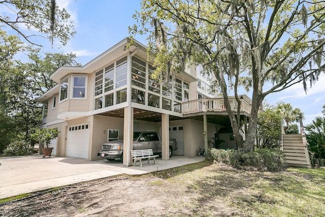 4702 Blockhouse Ln, Hollywood, SC 29449 - back of house featuring an attached garage, concrete driveway, stucco siding, a deck, and a sunroom