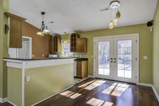 kitchen featuring french doors, pendant lighting, dark countertops, brown cabinetry, and dark wood-type flooring