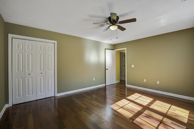 unfurnished bedroom featuring a textured ceiling, dark wood-style flooring, and baseboards