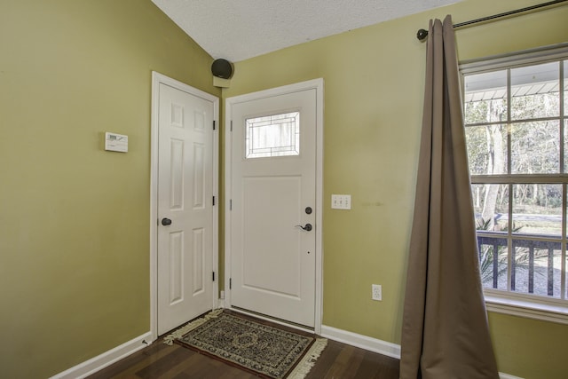 foyer entrance featuring dark wood-style flooring, a textured ceiling, and baseboards