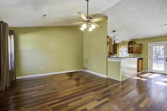 kitchen with baseboards, visible vents, brown cabinetry, dark wood-style flooring, and a peninsula