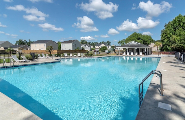 community pool featuring a residential view, a patio area, and fence