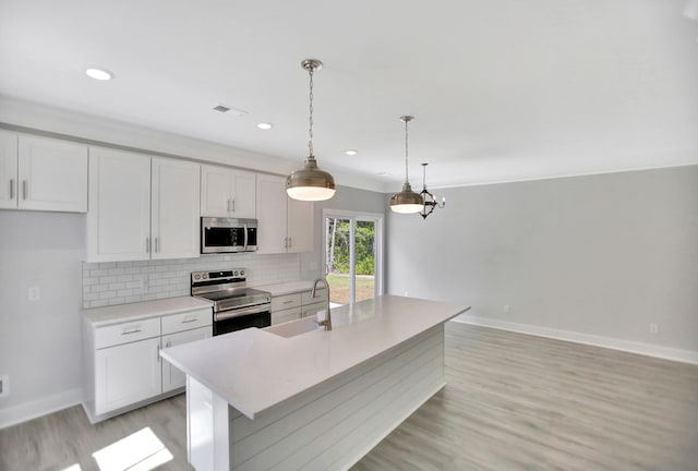 kitchen featuring sink, white cabinetry, hanging light fixtures, stainless steel appliances, and a kitchen island with sink