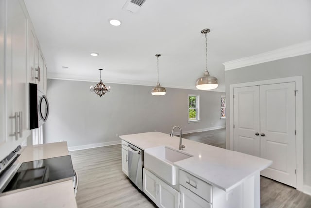 kitchen featuring appliances with stainless steel finishes, white cabinetry, sink, hanging light fixtures, and a kitchen island with sink