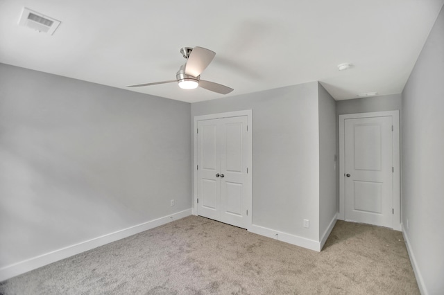 unfurnished bedroom featuring light colored carpet, a closet, and ceiling fan