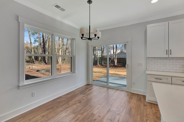 unfurnished dining area featuring an inviting chandelier and light wood-type flooring