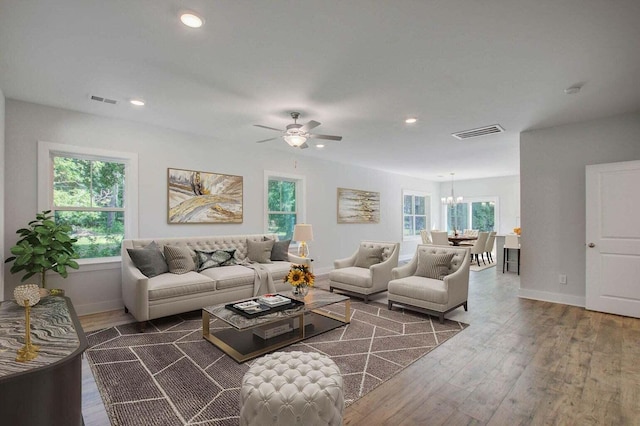 living room with ceiling fan with notable chandelier and dark wood-type flooring