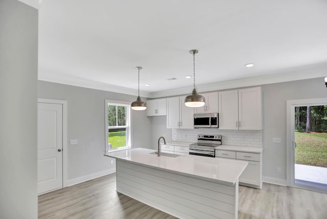 kitchen featuring sink, tasteful backsplash, decorative light fixtures, a center island with sink, and appliances with stainless steel finishes