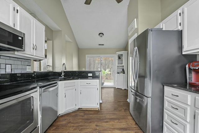 kitchen featuring appliances with stainless steel finishes, dark wood-type flooring, white cabinets, a sink, and a peninsula