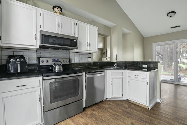 kitchen with appliances with stainless steel finishes, white cabinets, a sink, and a peninsula