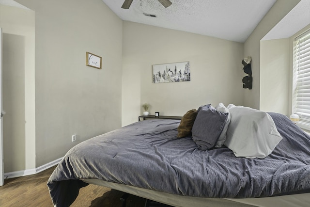 bedroom with visible vents, a ceiling fan, vaulted ceiling, wood finished floors, and baseboards