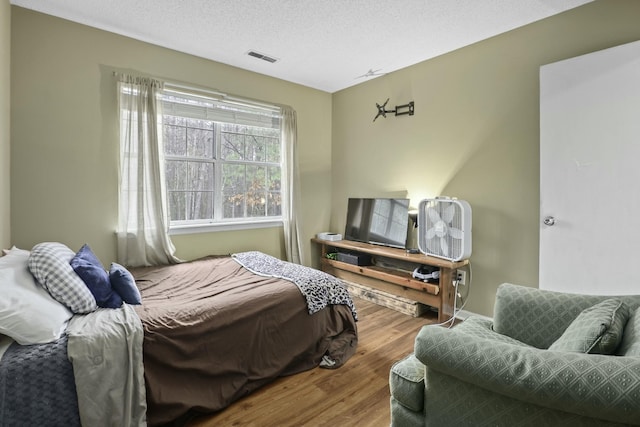 bedroom featuring a textured ceiling, wood finished floors, and visible vents