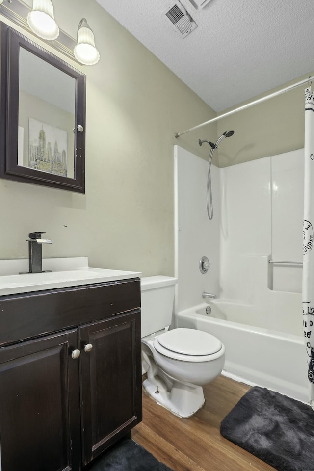 full bathroom with a textured ceiling, toilet, wood finished floors, vanity, and visible vents