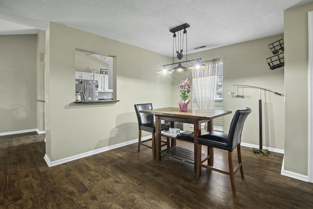 dining space with dark wood-style floors, baseboards, visible vents, and a textured ceiling