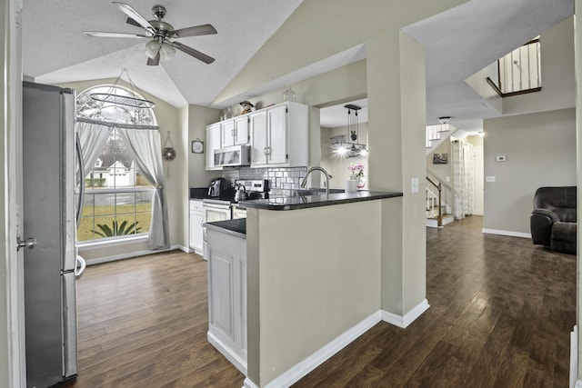 kitchen with tasteful backsplash, dark countertops, dark wood-style floors, lofted ceiling, and appliances with stainless steel finishes