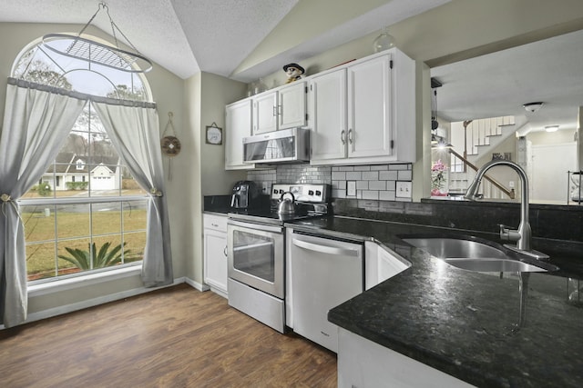 kitchen with dark wood-style flooring, tasteful backsplash, appliances with stainless steel finishes, vaulted ceiling, and a sink