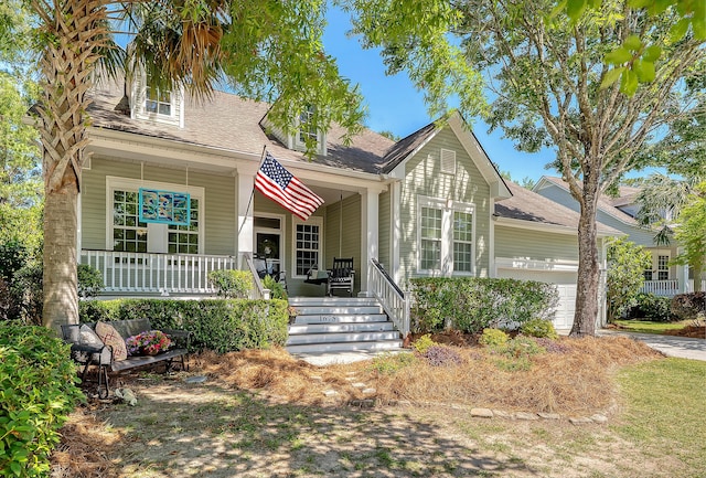 view of front of property featuring a garage, covered porch, and roof with shingles