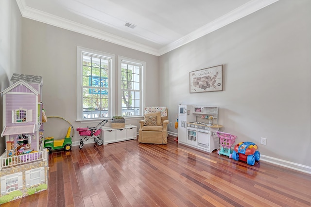 rec room featuring visible vents, ornamental molding, baseboards, and hardwood / wood-style flooring