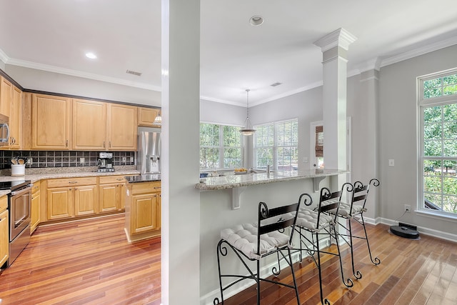 kitchen with appliances with stainless steel finishes, light brown cabinets, a breakfast bar area, and light wood-style flooring