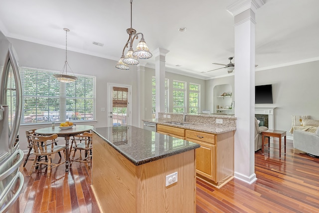 kitchen featuring ornate columns, a sink, appliances with stainless steel finishes, and hardwood / wood-style flooring