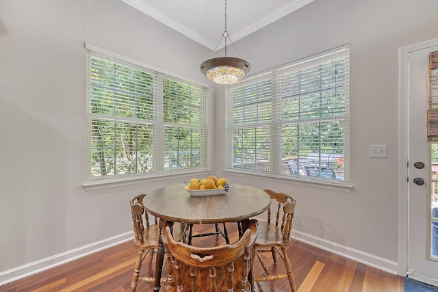 dining area featuring a healthy amount of sunlight, baseboards, ornamental molding, and wood finished floors