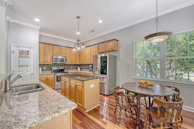 kitchen featuring backsplash, appliances with stainless steel finishes, a center island, wood finished floors, and a sink