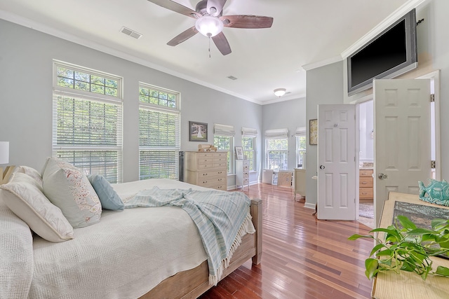 bedroom featuring crown molding, wood-type flooring, a ceiling fan, baseboards, and visible vents