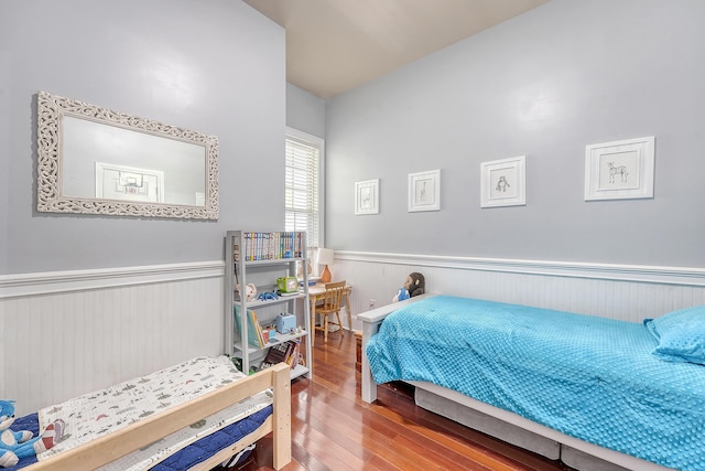 bedroom featuring wainscoting and wood finished floors