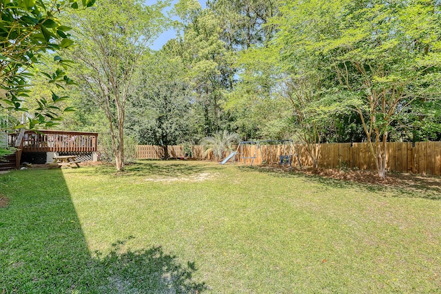 view of yard with a deck, a fenced backyard, and a playground