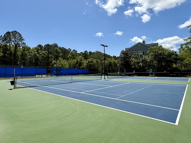 view of tennis court featuring community basketball court and fence
