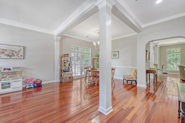 interior space with crown molding, ornate columns, and wood finished floors
