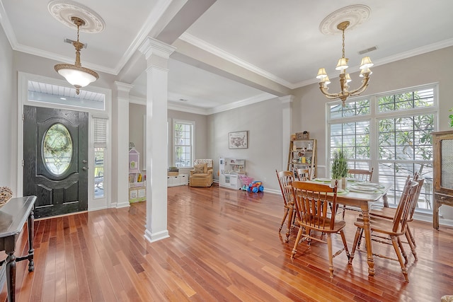 entrance foyer with visible vents, crown molding, decorative columns, wood finished floors, and a chandelier