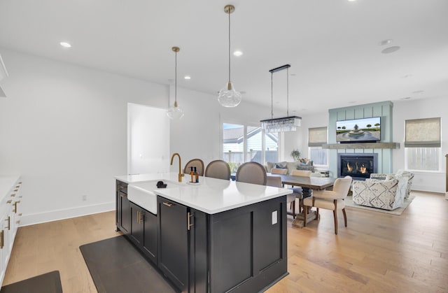 kitchen with light wood-type flooring, an island with sink, a sink, open floor plan, and recessed lighting