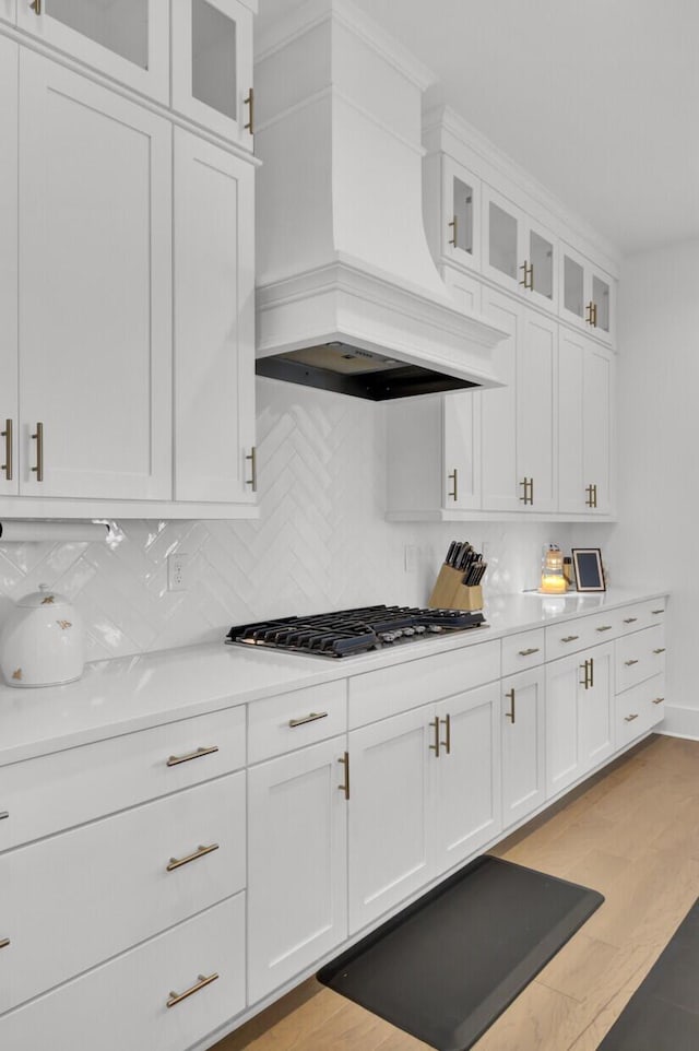 kitchen featuring premium range hood, light countertops, decorative backsplash, stainless steel gas stovetop, and white cabinets