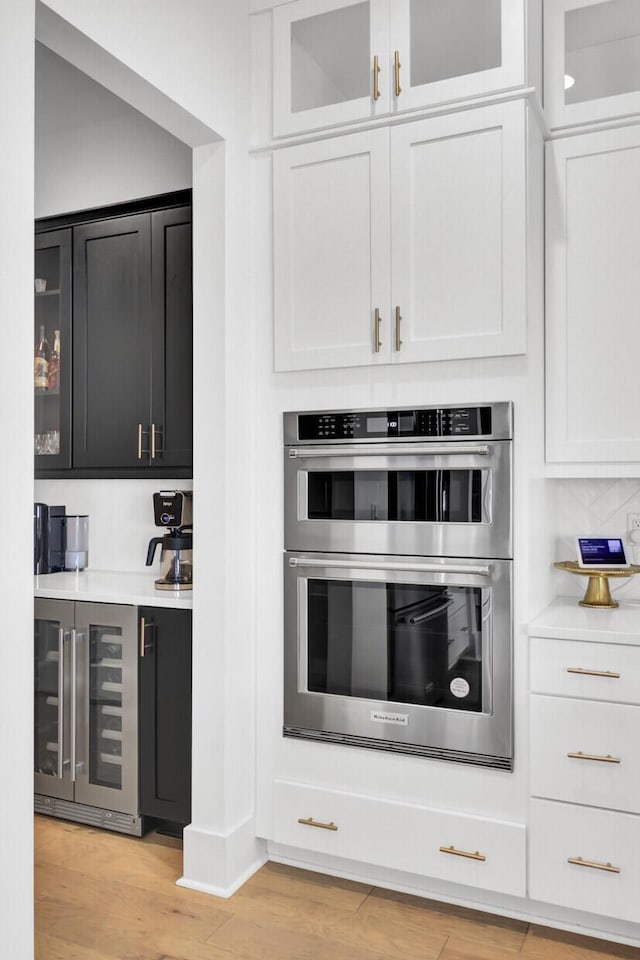 kitchen featuring light countertops, wine cooler, light wood-style floors, and stainless steel double oven