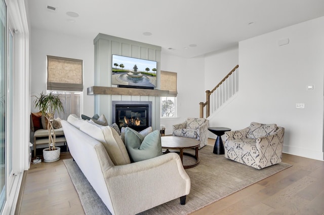 living area with a fireplace, wood finished floors, baseboards, and a wealth of natural light