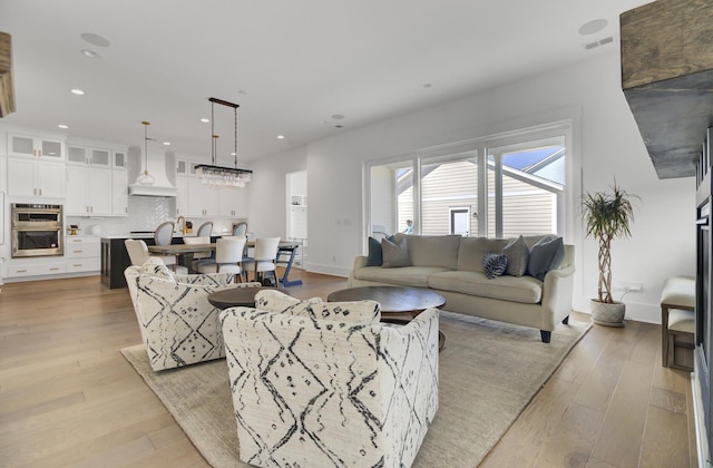 living room featuring light wood-style flooring, recessed lighting, visible vents, and baseboards