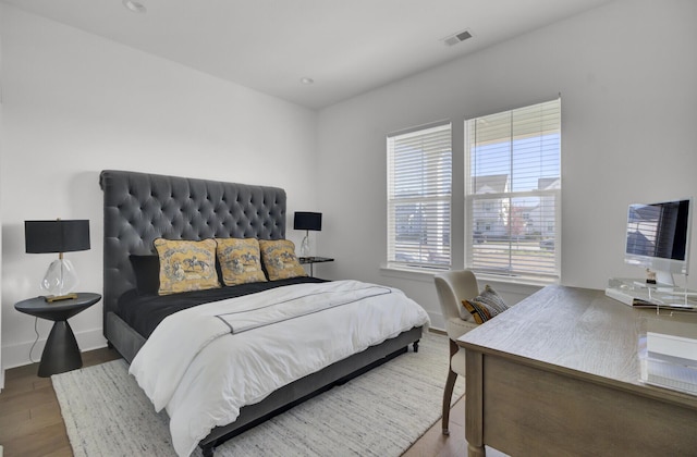 bedroom with visible vents, baseboards, and wood finished floors