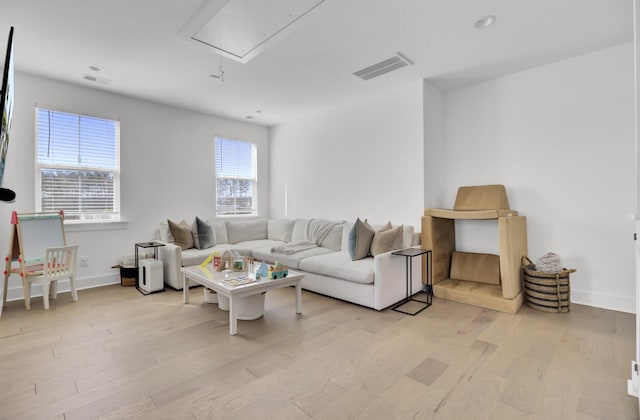 living room with attic access, baseboards, visible vents, and light wood finished floors