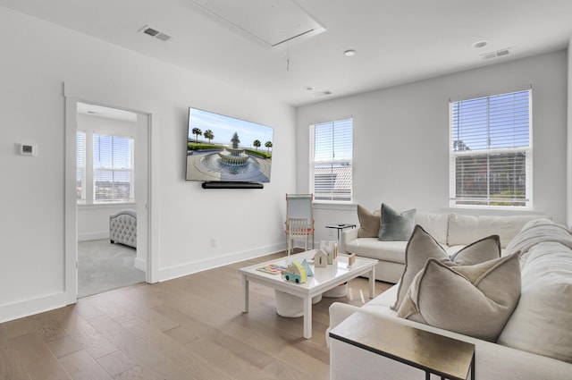 living room with a wealth of natural light, visible vents, attic access, and wood finished floors