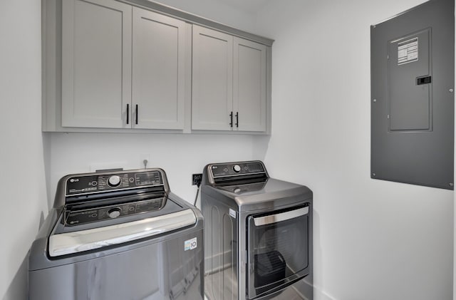 clothes washing area featuring electric panel, cabinet space, and washer and clothes dryer