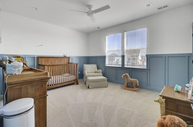 carpeted bedroom with visible vents, a wainscoted wall, a ceiling fan, recessed lighting, and a decorative wall