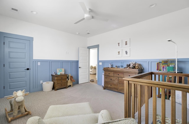 carpeted bedroom featuring recessed lighting, ceiling fan, wainscoting, and a decorative wall