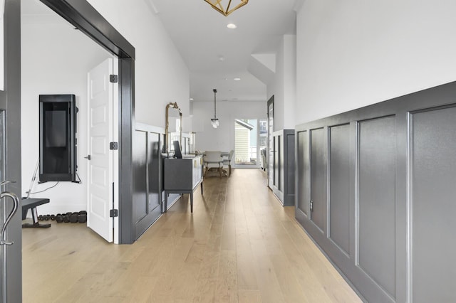 hallway with a high ceiling, recessed lighting, and light wood-style floors