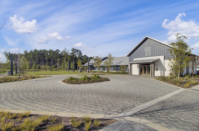 view of front of property featuring a standing seam roof, a garage, decorative driveway, board and batten siding, and metal roof